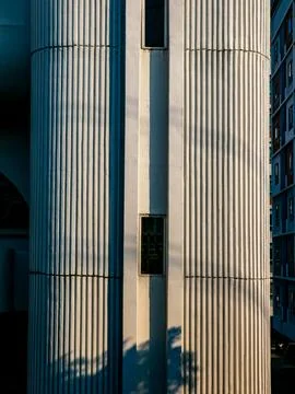 Architectural contrast between an arched window building and a white ribbed.. 스톡 사진