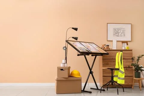 Architectural design workspace with drafting table, safety gear, and building Stock Photos