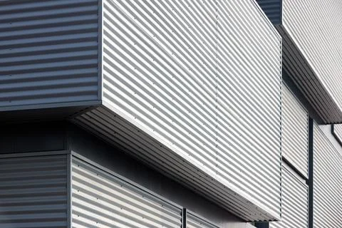 Architectural facade with gray cladding corrugated metal panels of industrial Stock Photos