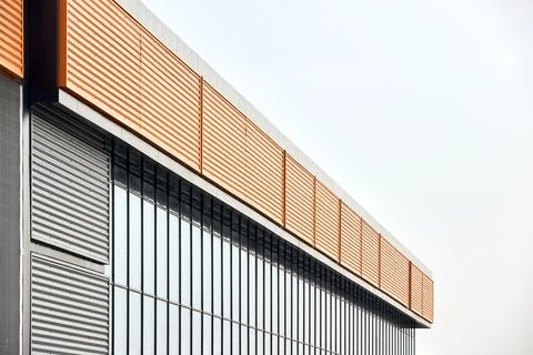 Architectural facade with orange cladding corrugated metal panels, large glas Stock Photos