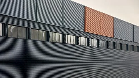 Architectural facade with orange cladding corrugated metal panels, large glas Photos