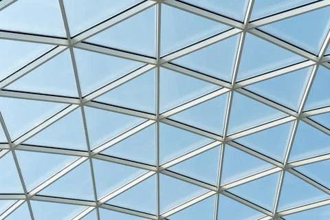 Architectural glass structure with a geometric triangular pattern on a blue s 스톡 사진