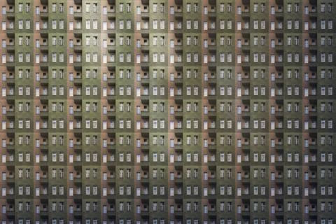 Architectural pattern, dark facade with windows and balconies of a miserable  Stock Photos
