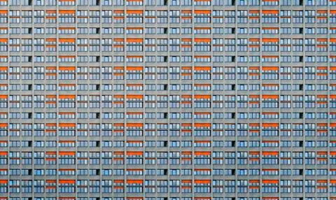 Architectural pattern, window facade with orange shutters of a skyscraper Stock Photos