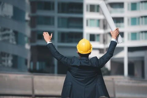 Architecture Engineer raised hands and holding blueprint to showing success b Stock Photos