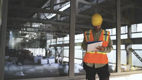 Architengineer with hard hat holding blueprint and inspecting construction site Stock Footage 159749208