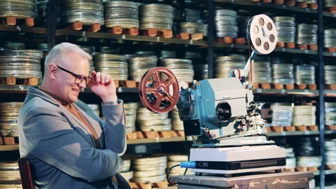 Archive specialist is laughing next to the antique film projector Vídeo Stock 151891336