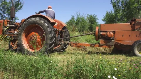 Arcing shot around farmer baling hay with an old tractor and hay baler. Stock Footage 117306433