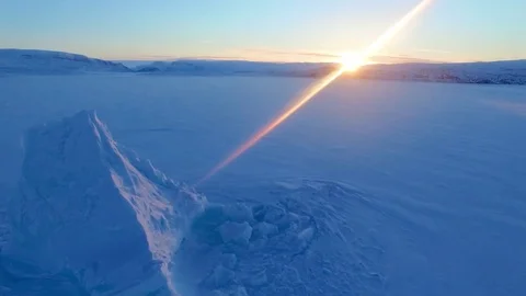 Arctic aerial shot of a glacier frozen into a lake with the morning sun on the Stock Footage