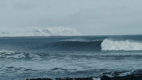 Arctic lineup surf wave breaks with snow mountains in background bird flying 4K Stock Footage 128752305