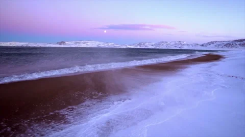 Arctic ocean waves on a snowy winter beach at sunset Stock Footage 337060971