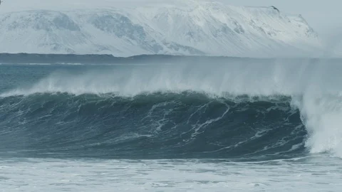 Arctic surfer tries to catch wave breaks with snow mountains in background 4K Stock Footage 128757130