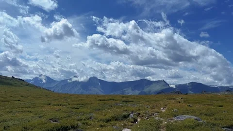Arctic tundra landscape, mountain range distant, dramatic cumulus clouds, wide 動画素材 347349804