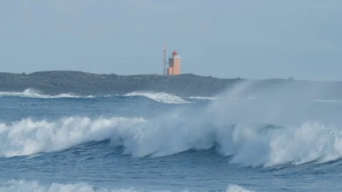 Arctic wave breaks with lighthouse in background 4K Stock Footage 128755417