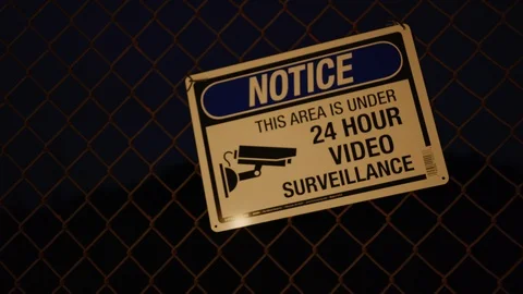 This Area Is Under 24 Hour Video Surveillance signs at fence at night Stock Footage 126688545