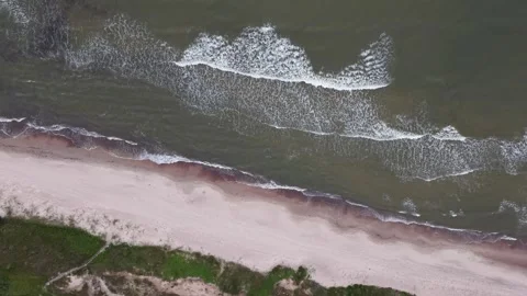 Areal drone shot looking down at sea waves on sandy shore Stock Footage 341770261