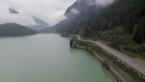 Areal footage of traffic on road surrounded by alps Stockbeeldmateriaal 252151241