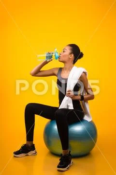 Arfo Fitness Girl Sitting On Fitball Drinking Water, Studio Shot Stock Photos