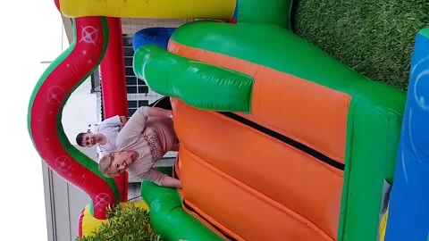 Argentina: Grandmother slips while playing on inflatable slide with grand... Stock Footage 333449905