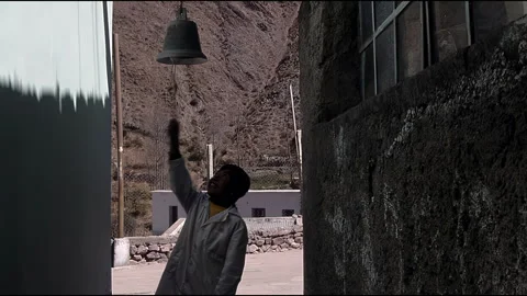 Argentine Boy Pulling Rope to Ring Traditional Metal Bell in Mountain Village 4K Stock Footage 337475625