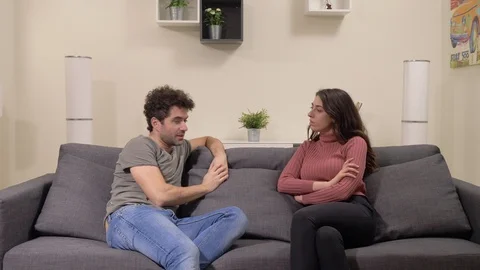 Argue,discussion,problems.Young lovers sitting on couch arguing about their love Stock Footage 116413932
