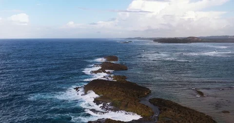 Arial shot gaining altitude over a limestone outcrop off an Atlantic ocean beach Stock Footage 124744180