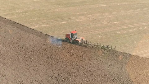 Arial shot of a tractor plows a field with a plow Stock Footage 123489870