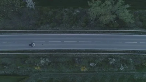Arial: Single car driving by on highway road between meadows with trees, 4K Stock Footage 74688297