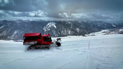 Arial of a snowcat as it tracks along a mountain top in Idaho Stock Footage 230770963