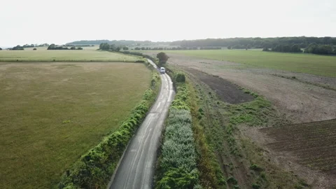 Arial view from Drone following campervan on scenic road trough fields at sunset Video stock 133097707