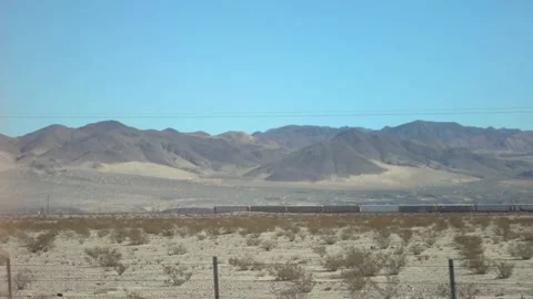 Arid desert landscape with sparse vegetation, distant mountains, and clear .. Stock Footage 281276787