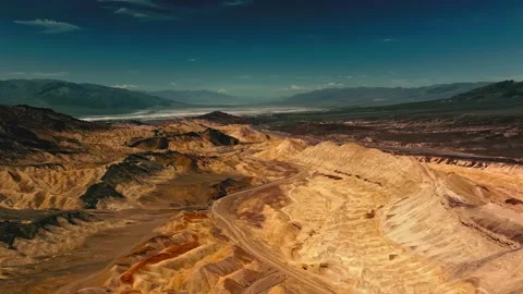 Arid desert valley with winding road and dramatic mountain backdrop, drone Stock Footage 343696217