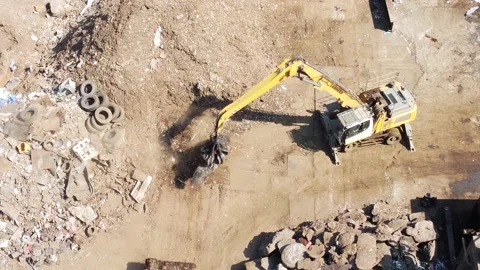 Ariel Drone Shot of Large Crane With Claw Sweeping Ground in Scrap Yard Stock Footage 194152102