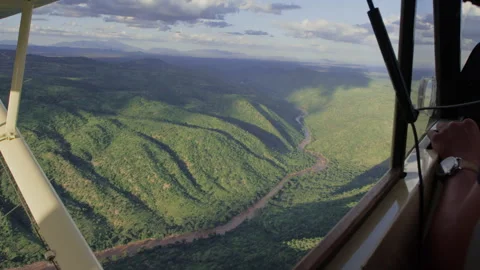 Ariel of a river flowing through valleys within the savannah Stock Footage 261026377