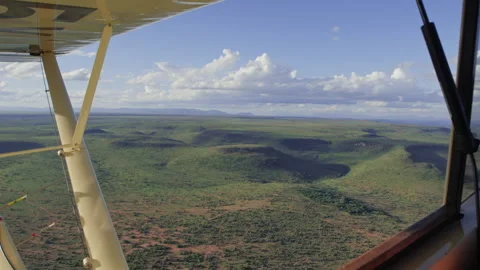 Ariel of valleys within the savannah from a light aircraft in Kenya Video stock 261026099