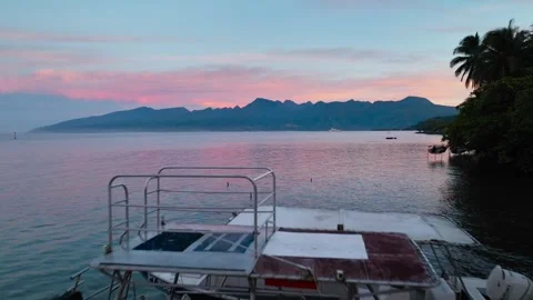 Aris 2024 Olympic logo marks dive boat docked at wooden pier beneath pink Stock Footage 341853531