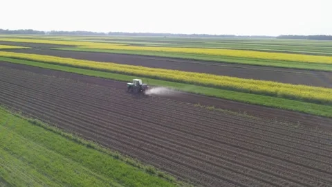 Ark Dolly Shot - Tractor spraying fields in vibrant rural landscape Stock Footage 148399549