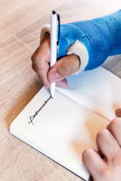 Arm with blue cast and notepad 库存照片