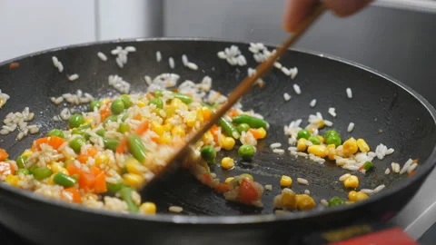 Arm of chef stirring rice with mixed vegetables using a spatula on frying pan Vídeos de archivo 146647435