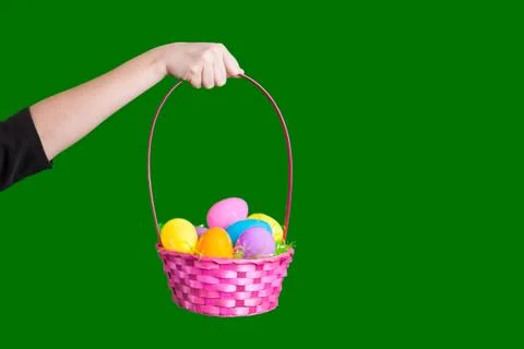 Arm holding up a Easter egg basket filled with plastic eggs on green screen Stock Photos