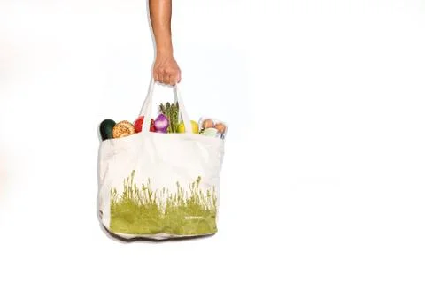 An arm holding an organic bag with different healthy foods on a white backgro Stock Photos