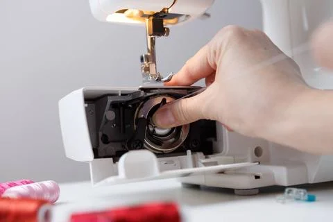 Arm inserts bobbin in sewing-machine Arm inserts bobbin in sewing machine ... 写真素材