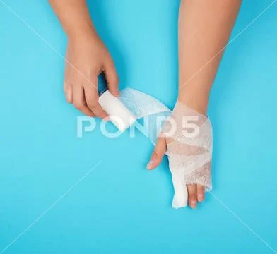 Arm wrapped in a white sterile bandage on a blue background Stock Photos