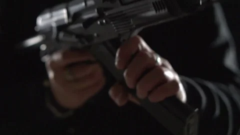 Armed man in black reloads an machine gun. Bandit with weapons in hand on a Stock Footage 83001244