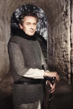 Armed man in chain armor with sword serving as guard on castle gateway Stock Photos