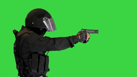 Armed man in protective cask with a pistol walking aiming on a Green Screen 動画素材 148573875