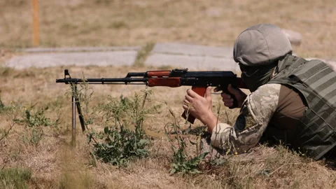 Armed man unloading machine gun with machine gun in his hands, soldier lying Stock Footage 217371434