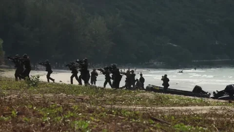 Armed marines advancing up beach during amphibious assault Stock Footage 269132627