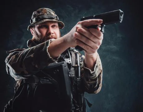 Armed with modern handgun guy in camouflage equipment Stock Photos