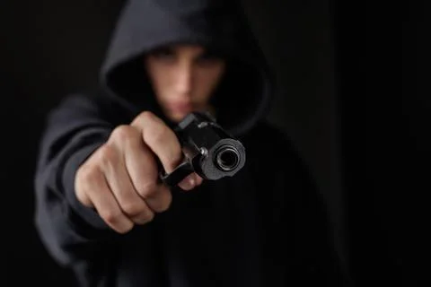 Armed Robber Pointing Gun in Dark Setting Stock Photos